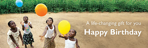 A life-changing gift for you. Happy Birthday. Four children standing in front of a lush, green field, launching three balloons in the air.